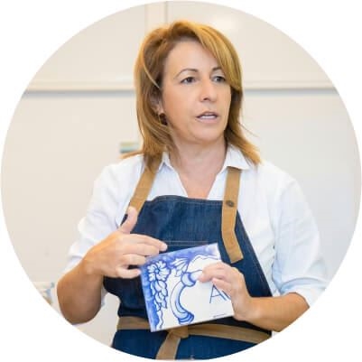 A female substitute teacher holding a small canvas in an art class